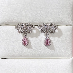 Detailed view of silver bow earrings with pink teardrop gems and pavé set crystals