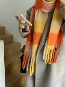 Detail of thick rainbow plaid scarf with orange and yellow stripes and long tassels