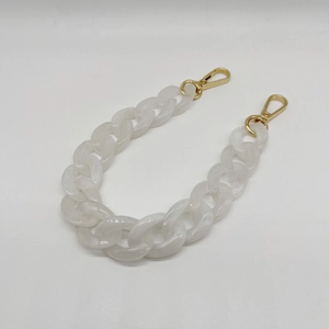 Close-up of white acrylic fishbone chain with gold lobster clasps for bags and glasses
