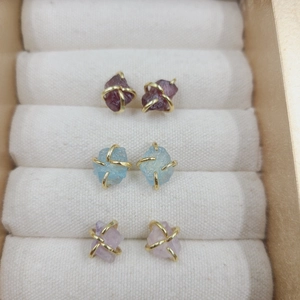 Detail of amethyst and natural stone stud earrings with gold wire wrap in a velvet box
