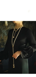 Dettaglio dell'elegante collana di perle a più strati con ciondolo a uccello vintage