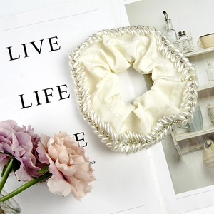 Detailed close-up of cream satin scrunchie featuring elegant pearls and sparkling rhinestones