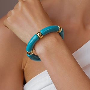 Dettaglio di perle acriliche verde petrolio e metallo dorato su un bracciale moderno