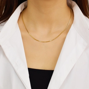 Close-up of a layered gold snake chain necklace with a heart pendant on a model