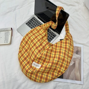 Macro shot of large yellow plaid canvas tote bag with brand label on laptop