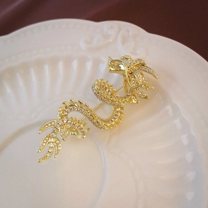 Detailed view of a gold-plated dragon brooch with sparkling crystals on a ceramic plate
