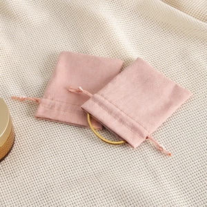Detail view of light pink microfiber drawstring jewelry pouch with a gold bracelet