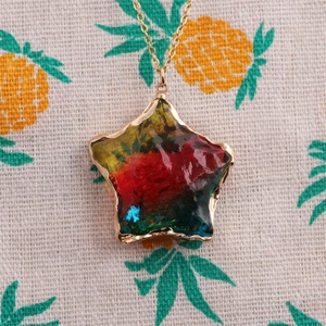 Close-up of gold-rimmed star pendant with colorful resin inlay on a steel chain