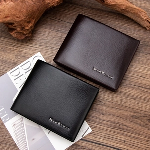 Detail view of textured leather bifol wallets in black and dark brown on wooden surface