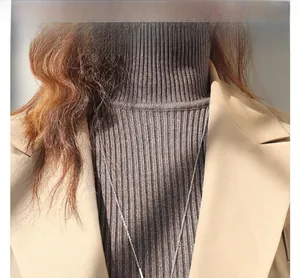 Dettaglio della collana a cuore su lupetto marrone e blazer color kaki elegante