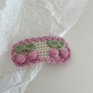 Detail of handmade crochet hair clip with pink cherry embroidery and knit textures