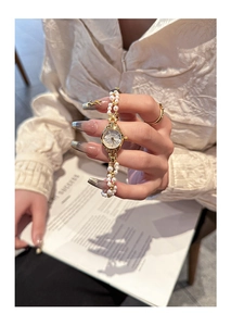 Detailed close-up of a vintage gold steel watch with elegant pearl chain bracelet