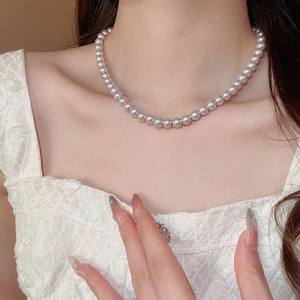Detailed view of elegant pink pearl strand necklace on model neck with lace dress