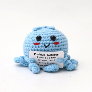 Blue crochet octopus plushie holding a white positive quote card for desk decor