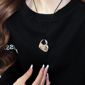 Close-up of silver hollow double heart pendant on black cord worn by a model