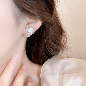 Boucles d'oreilles flocon de neige argentées avec perles portées par un mannequin