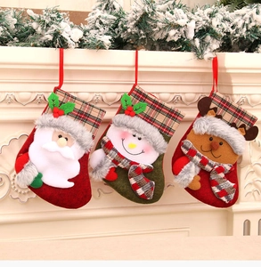 Three plush Christmas stockings with Santa, Snowman, and Reindeer hung on a festive mantel