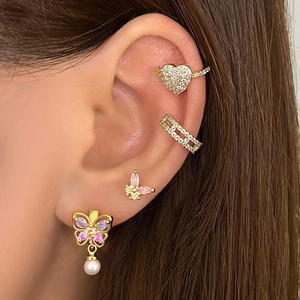 Boucles d'oreilles papillon dorées avec zircon et perles sur un mannequin femme