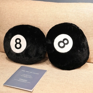 Detail of two black number 8 billiards cushions on a beige textured sofa with a magazine