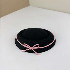 Detail of black wool felt boater hat with pink velvet ribbon and a sweet bow decoration