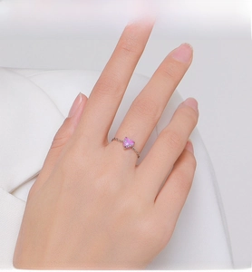 Close-up of pink heart opal sterling silver chain ring worn on finger