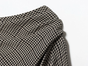 Detail shot of black and white houndstooth pattern fabric with elegant pleated waist design