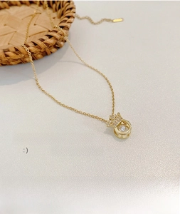Macro detail of gold plated angel wing crown necklace with dancing stone zircon pendant