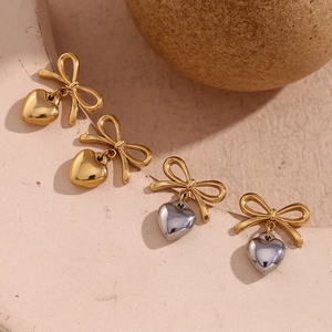 Détail des boucles d'oreilles nœud et cœur plaquées or 18 carats sur pierre texturée