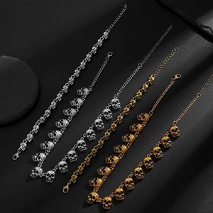 Gedetailleerde punk schedelarmbanden in zilver, goud en brons op zwarte natuursteen