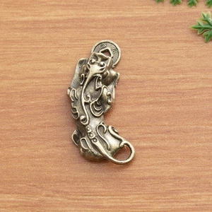 Macro detail of brass Pixiu pendant with antique finish and lucky coin on wooden background