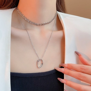 Detail of silver double layered chain necklace with an irregular oval pendant on a model