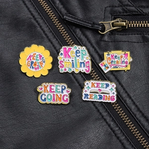 Detail of five motivational enamel pins on a leather jacket with Keep Smiling text