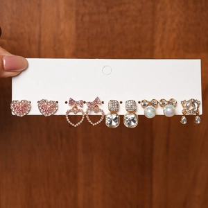 Vue détaillée d'un lot de six paires de boucles d'oreilles avec cœurs roses et perles sur carte