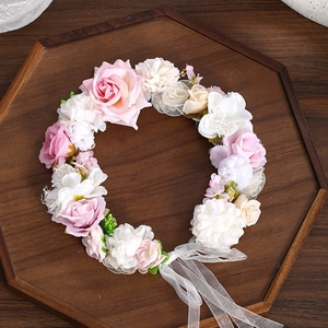 Detail showing artificial pink roses, lace mesh, and ribbons on a floral headband