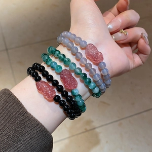 Close-up of stacked beaded Pi Xiu bracelets in black, green, and grey-blue tones