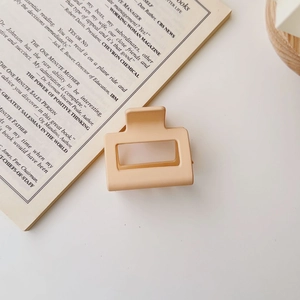 Detail of a matte light orange square hair claw clip placed on an open book page