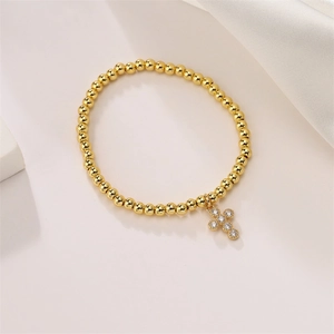 Detailed close-up of 4mm gold beaded bracelet featuring a cross pendant with clear zircons
