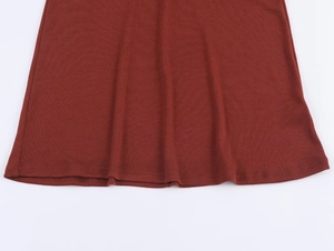 Détail de couture de l'ourlet et texture tricotée de l'ensemble haut et jupe rouge foncé