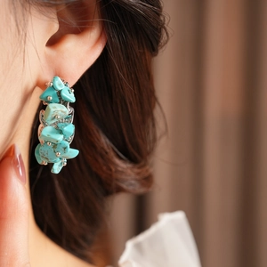 Gros plan de boucles d'oreilles en C argentées avec pierres turquoise irrégulières
