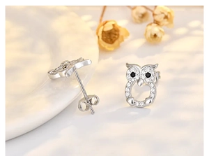 Macro detail of silver owl stud earrings with cubic zirconia and black gemstone eyes