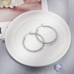 Detailed macro view of silver twisted rope hoop earrings on a decorative ceramic tray