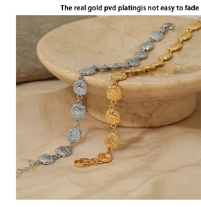 Detail of PVD gold plated textured square chain bracelet on beige marble surface