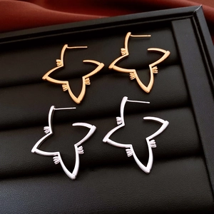 Detail of star-shaped 18K gold and silver hollow earrings on a black leather display