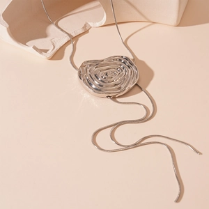 Détail du pendentif tourbillon argenté avec chaîne serpent fine sur un support moderne