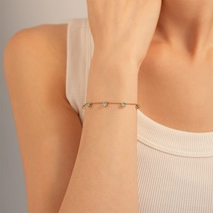 Detail of 18K gold beaded bracelet featuring five light blue round gemstone pendants