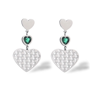 Macro shot of silver heart earrings with green gemstone and filigree flower details