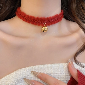 Gros plan d'un ras-du-cou en tricot rouge avec un pendentif clochette doré brillant