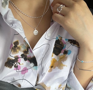 Detail of S925 sterling silver layered necklace with smiley pendant and turquoise bracelet
