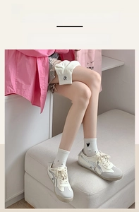 Close-up of white ribbed crew socks with embroidered heart detail and elastic cuffs