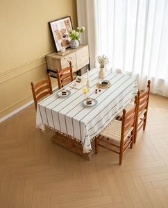 Detail of white cotton linen tablecloth with blue stripes and decorative tassel edges